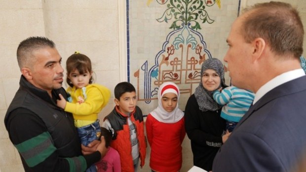 Immigration Minister Peter Dutton hands a refugee visa to the Syrian refugee family of Marwan Alkhdah in Jordan earlier this month. 