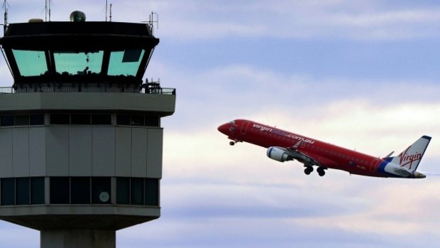 A plane takes off from Melbourne Airport, under the gaze of air traffic controllers.