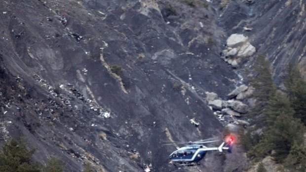 A rescue helicopter flies over debris of the Germanwings passenger jet.