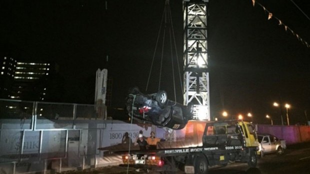 The car, which landed upside down in the pit, is removed from the site.