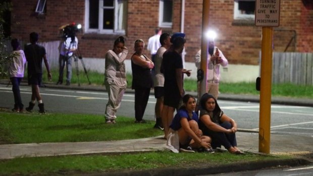 Papatoetoe residents look on as police investigate the scene of where a woman was thrown from her car.
