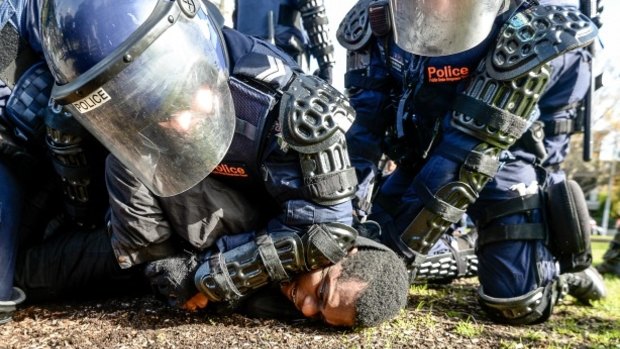 Police tackle a protester to the ground during the rally in Fitzroy Gardens. 