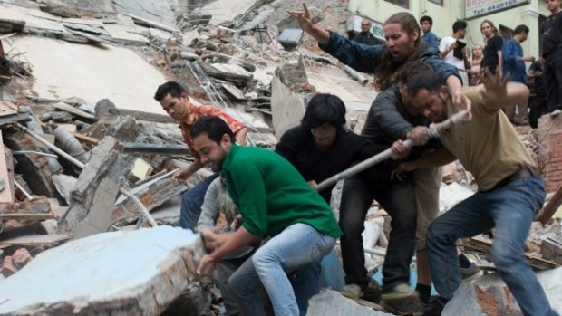 Men work to remove a body from the rubble of a collapsed building in Kathmandu.