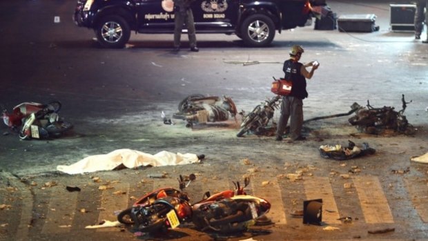 A policeman photographs debris from an explosion in central Bangkok, Thailand. 