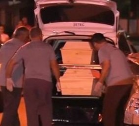 Funeral workers place coffins in a hearse after in a rare mass shooting in Brazil.