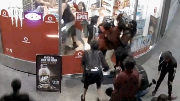 Young men and women loot the store while the shop-keeper is being attacked.
