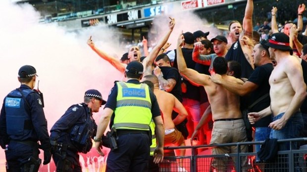 Fired up: Wanderers fans in the crowd let off flares as police officers look on during Saturday's match at  Etihad Stadium.