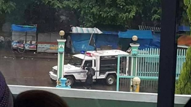 A seized police vehicle flies a black Islamic State-style flag on the streets of Marawi City on Tuesday.