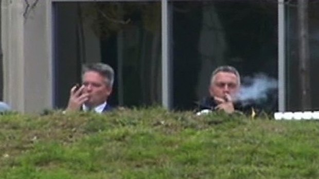 Finance Minister Mathias Cormann and Treasurer Joe Hockey enjoy cigars outside The Treasury in Canberra.
