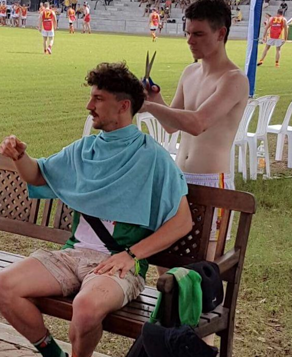 Tony Liberatore gets a haircut on the sidelines during a match with the Vietnam Swans.