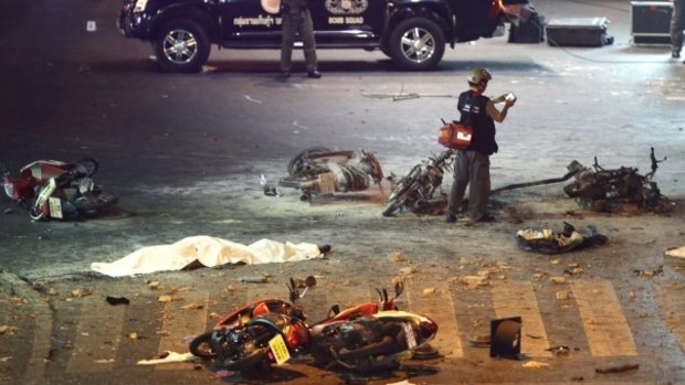 A policeman photographs the carnage after the bomb at the Erawan shrine.