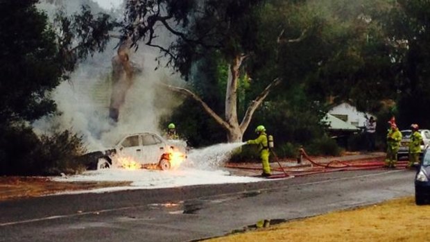 Firefighters battle to put out a car fire on Dryandra St, O'Connor. The car was struck by lightning, and is also above an underground gas leak.