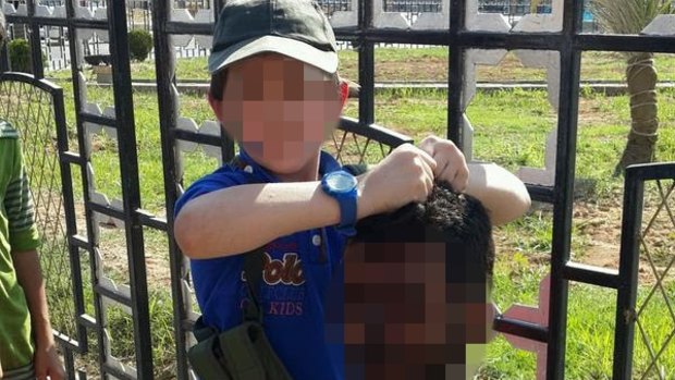 A boy security agencies believe to be Australian Khaled Sharrouf's son holds the decapitated head of a soldier in the Syrian city of Raqqa.