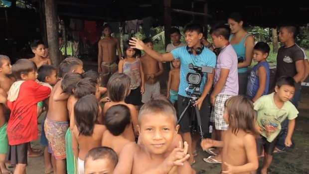 Romeu Iximawateri Yanomami, behind the camera, and Silvano Ironasiteri Yanomami, to his right, organise Yanomami children for a video shoot.