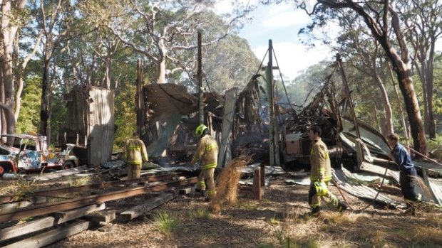 NSW Fire and Rescue officers sort through the remains of the destroyed storage shed at the Sydney Tramway Museum.