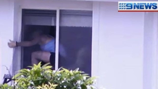 Police help a woman out of a Banyo house during a siege on Boxing Day 2013.