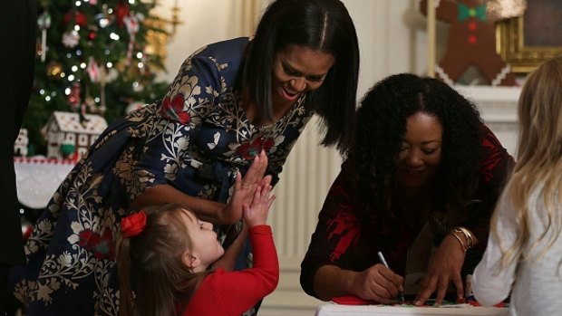 Michelle Obama high-fives a little girl in the State Dining Room as she hosts military families to the White House to view the 2016 holiday decorations. 