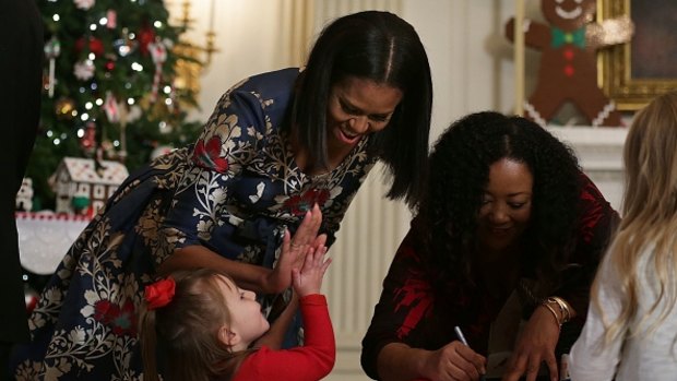 Flotus high-fives a little girl in the State Dining Room as she hosts military families to the White House to view 2016 holiday decorations.