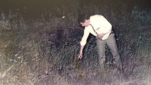 A police officer points to the spot where Michelle's necklace was found  near her body, in a photograph tendered to the court.