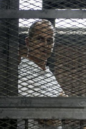 Peter Greste (left) listens to the verdict from the defendants' cage.
