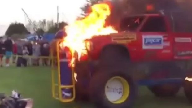 Tori Giles driven through walls of fire in a cage attached to the front of a monster truck.