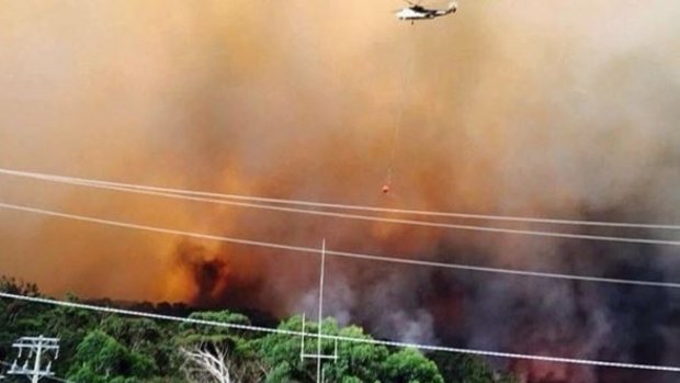 A helicopter waterbombs the Wye River fire.