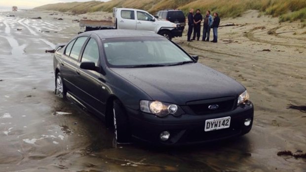 The car sits stranded on the beach.