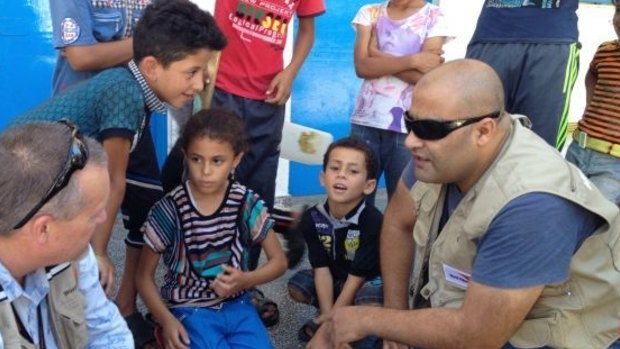 Mohammed Al Halabi, right, is seen talking to children in his work as Gaza program manager for World Vision.