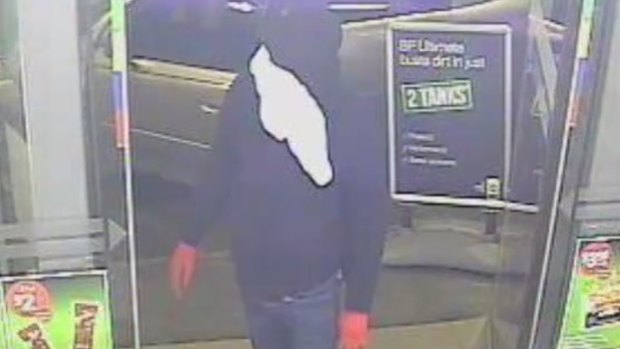 A masked man enters a service station in Brooklyn.