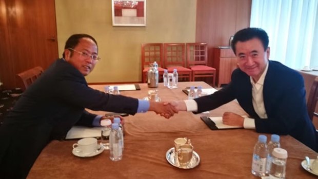 Huang Xiangmo, chairman of Yuhu Group, and entrepreneur Wang Jianlin of the Wanda group shake over the billion dollar deal.