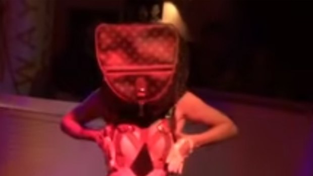 A striptease performer, wearing a bag on her head, emerges from a birthday cake at M&C Saatchi's 21st birthday party.