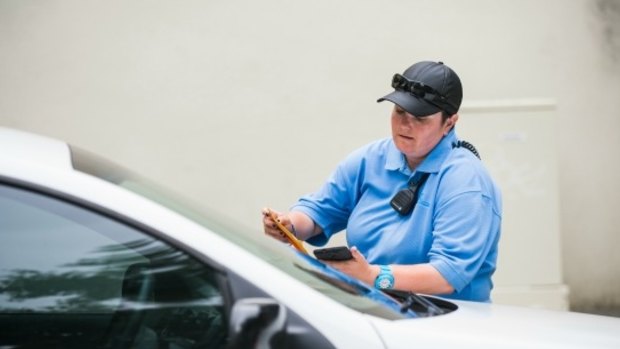 An ACT parking inspector leaves a ticket on the windscreen of a car. A Freedom of Information request revealed a stunning level of harassment of parking inspectors in Canberra. 