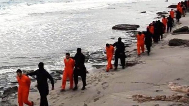 A screenshot from the video shows men being led along the beach. 