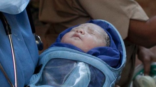 A newborn baby is transferred to an ambulance from a clinic in Anand, India, which has also banned surrogacy services for foreigners.