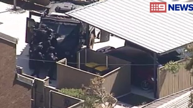 Police surround a man during a siege at an Inala home.