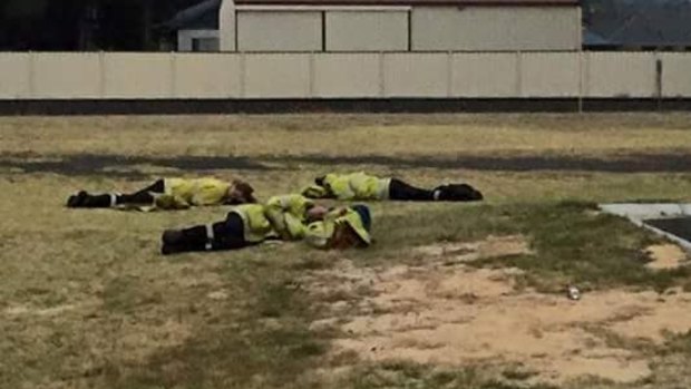 Exhausted firefighters kip on the lawn outside Harvey fire station during the Yarloop bushfire disaster. 