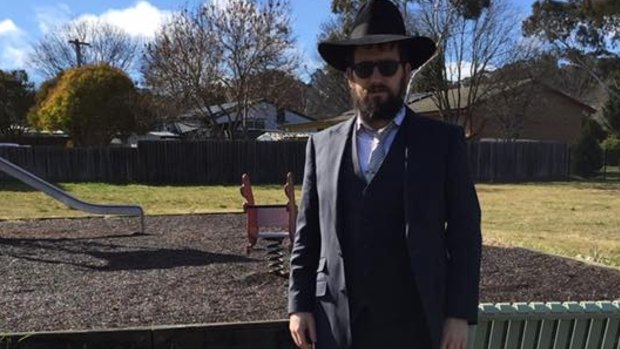 Rabbi Shmueli Feldman stands behind the graffiti near his synagogue in northern Canberra.
