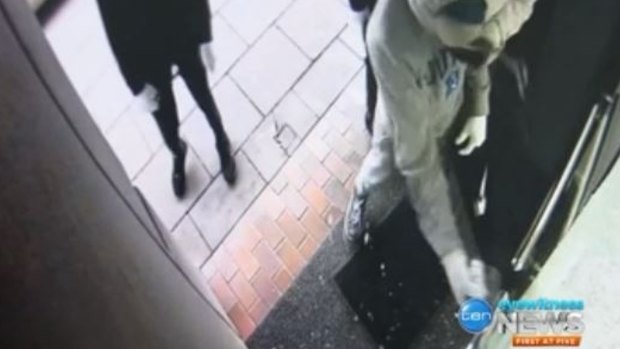 Two men using a crowbar and hammer to smash open the front door.