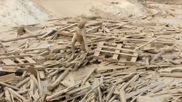 A woman climbs out of debris-filled floodwaters after being swept away in a mudslide in Peru.