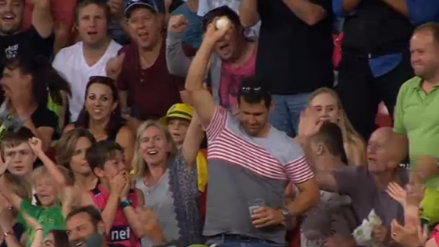 Howzat? A fan displays the ball after taking a one-handed catch without spilling his beer during the Thunder-Sixers Big Bash match.