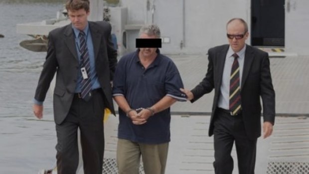 Steven Mark John Fennell being escorted by detectives after his arrest over the murder of Liselotte Watson on Macleay Island.