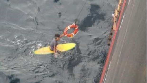 The man holds on to a life ring as he is pulled onto the MSC Damla.