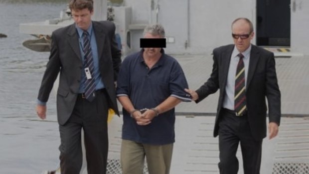 Steven Fennell escorted by detectives after his arrest over the murder of Liselotte Watson on Macleay Island.