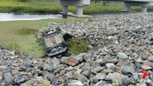 A car has rolled into a lagoon near Rockhampton, with the two occupants lucky to escape after the vehicle became partially submerged in the water.