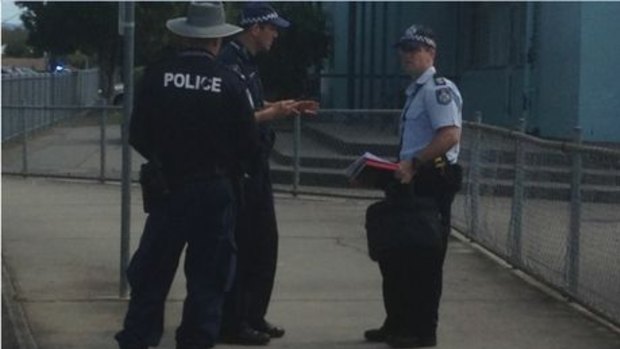 Police monitor an exclusion zone set up near Caboolture State High School.