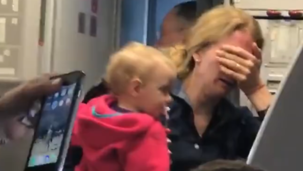 The distraught woman can be seen crying as she clutches her baby.