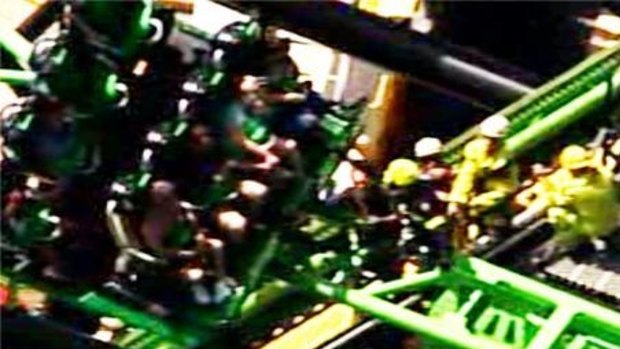Emergency service staff work to free six people  stranded on the Green Lantern ride at Movie World.