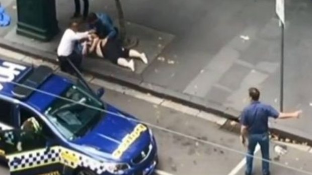 An image of Henry Dow and taxi driver Lou caring for a victim of the Bourke Street attack on Friday.