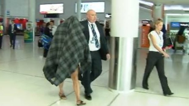 Police escort the accused transgender prostitute from Perth Airport.