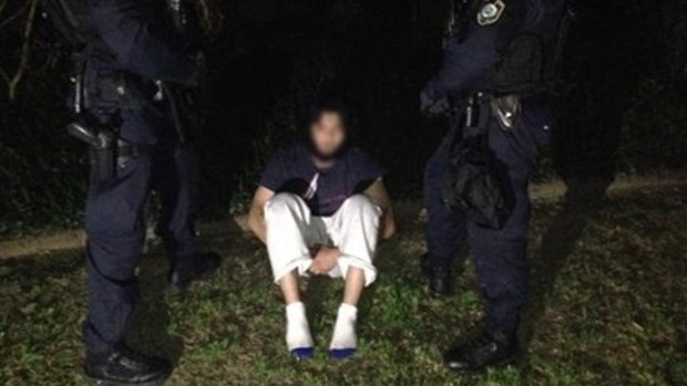Handcuffed: One of the terrorism suspects early onThursday.
